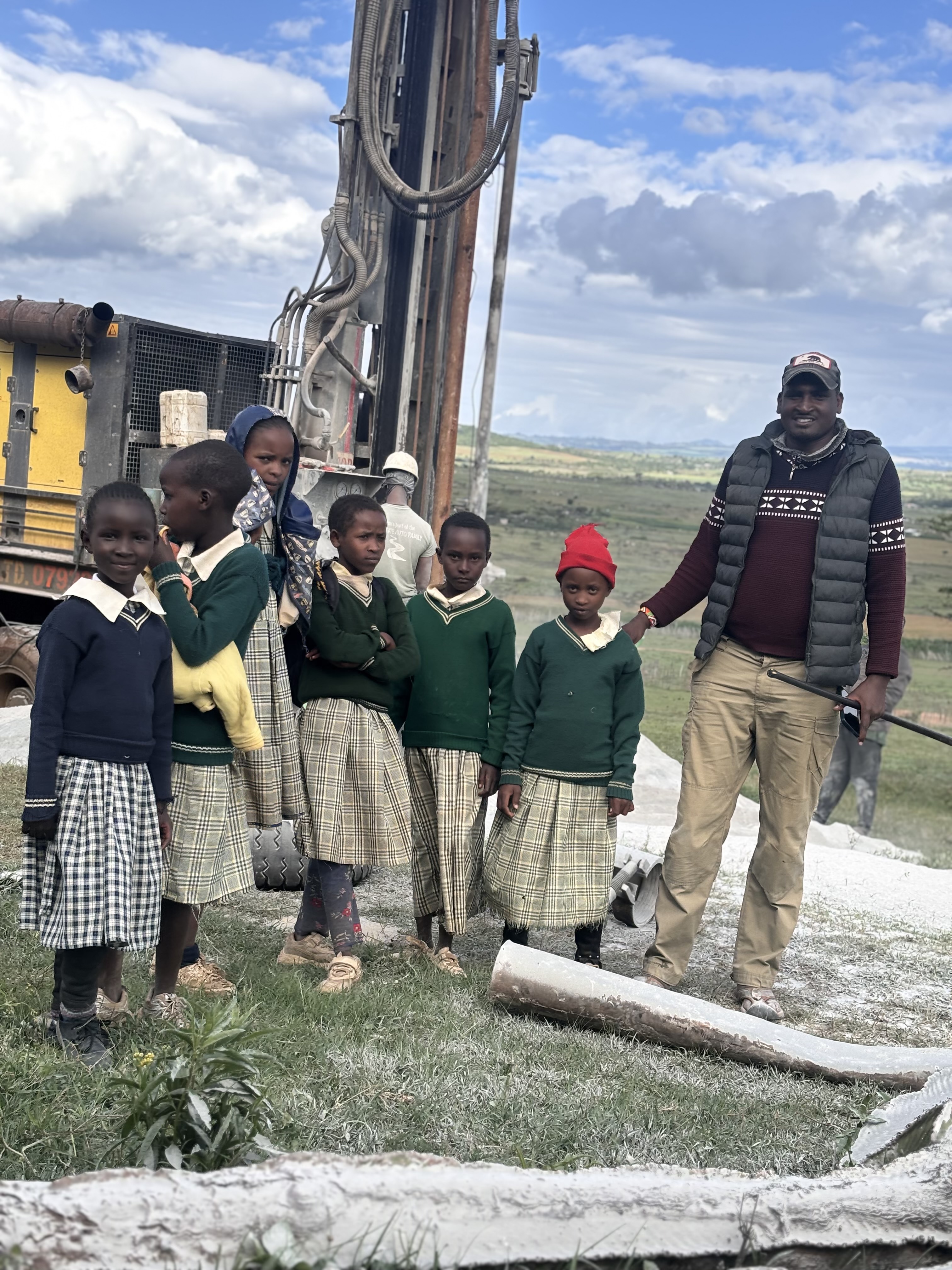 Community leader and schoolgirls beside Kisima drilling team Chumvi