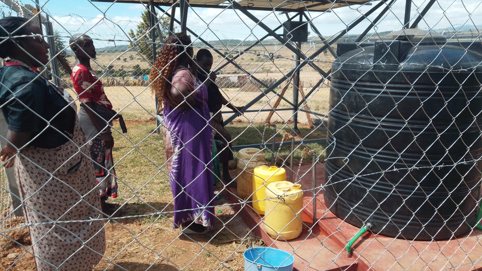 Women collecting water inside fenced Chumvi station